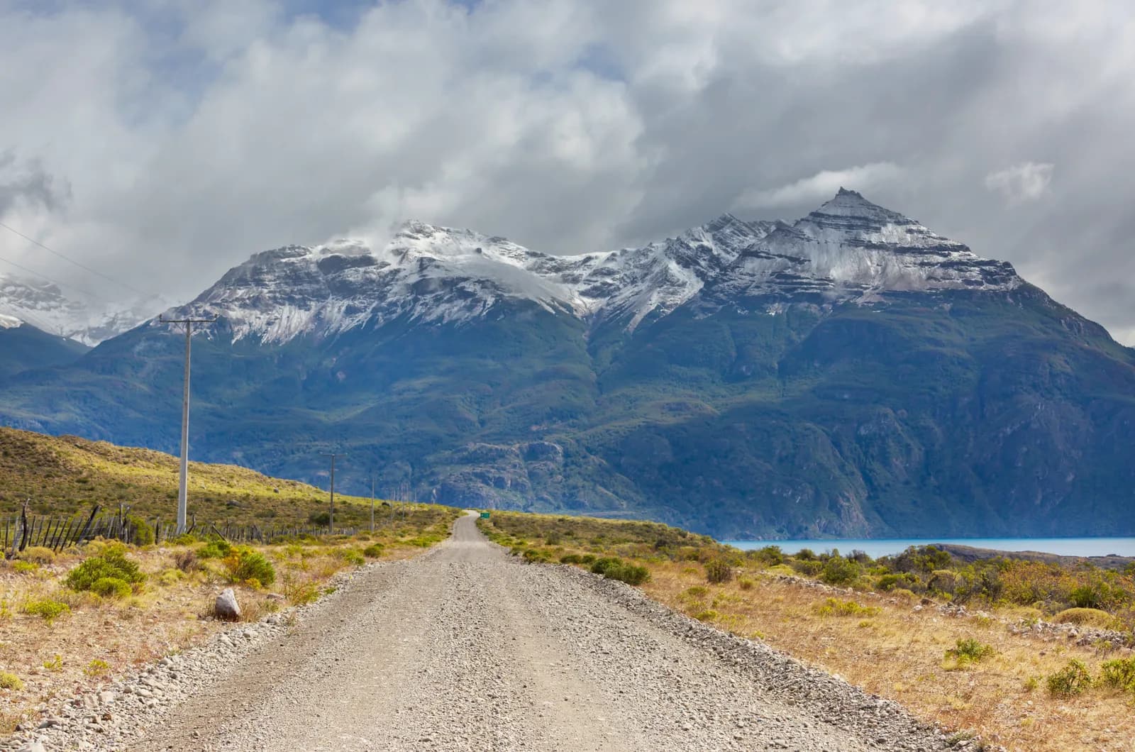 Tramo de ripio de la Carretera Austral avanzando hacia montañas nevadas en la Patagonia chilena